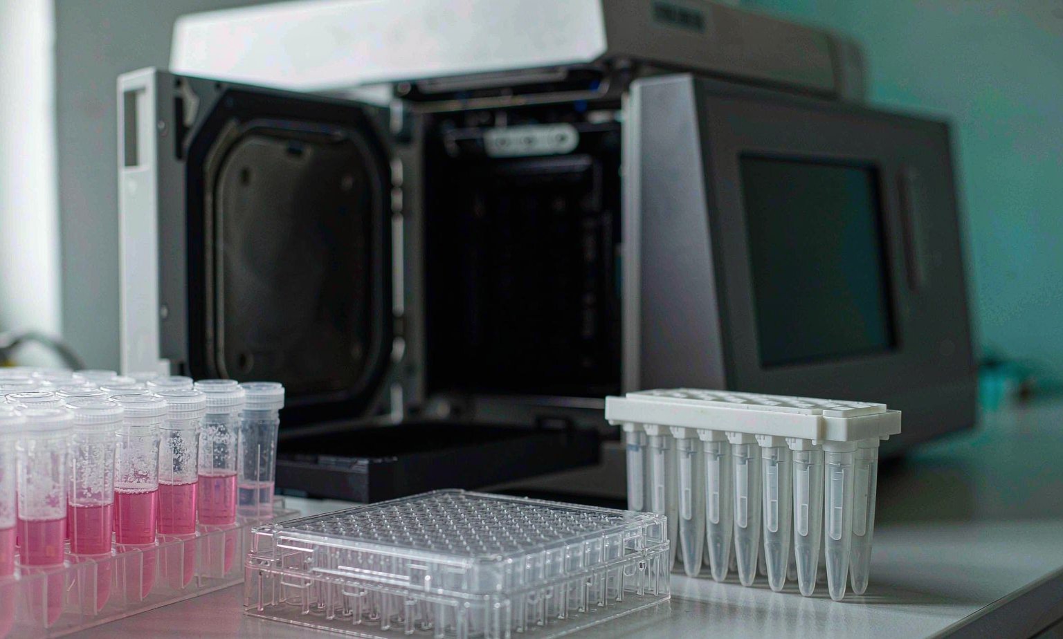 Real-Time PCR Plate and Cytology Sample Vials for High-Risk HPV Genotyping Molecular diagnostics laboratory bench with a 96-well real-time PCR plate, PCR tube strips in a rack and liquid cytology sample vials containing preservation fluid for high-risk HPV genotyping in cervical cancer screening