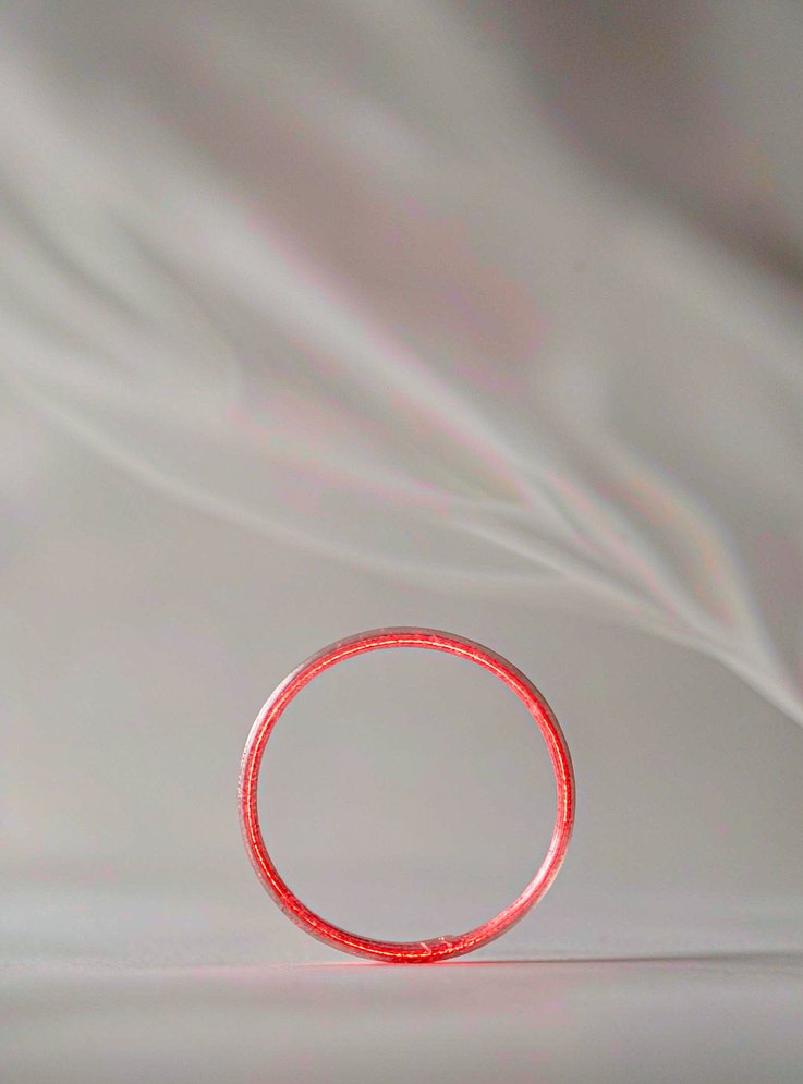 The Covalently Closed Loop Structure of Circular RNA Underpins Its Stability in Blood and Saliva An abstract glowing red ring resting on white fabric, representing the covalently closed loop structure of circular RNA that makes circRNA transcripts resistant to exonuclease degradation and stable in stored plasma and saliva specimens